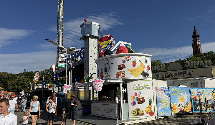 Jo Kurt Frozen Joghurt und im Hintergrund der Jules Verne Tower auf dem Gäubodenvolksfest 2025 (©Foto: Martin Schmitz)